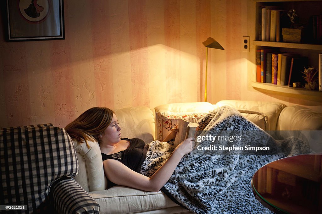 Teen girl reading on a short couch