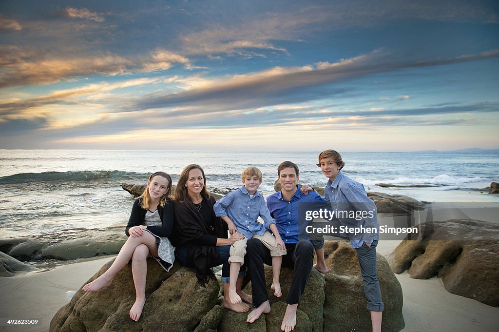 Family of five posing on seaside boulders