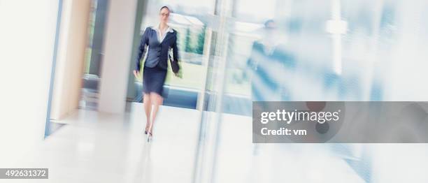 mulher de negócios andar em brighlty acesas escritório corredor - brightly lit imagens e fotografias de stock