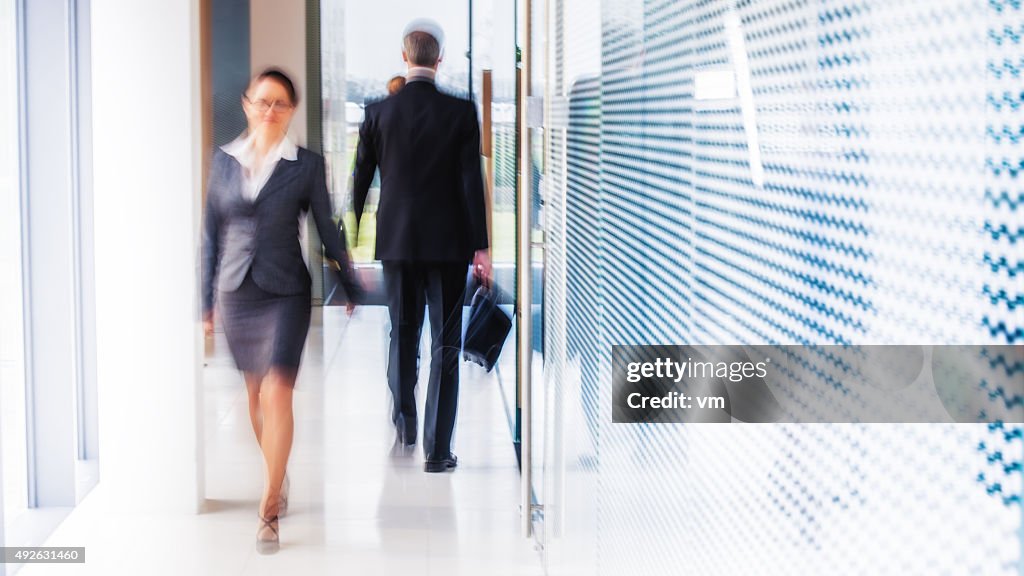 Defocused shot of business people walking in modern office corridor