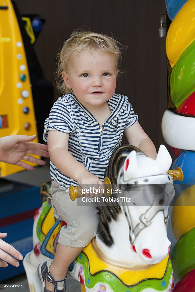 Baby boy riding an amusement ride horse