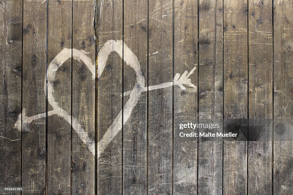 Heart shape with arrow symbol on wooden fence