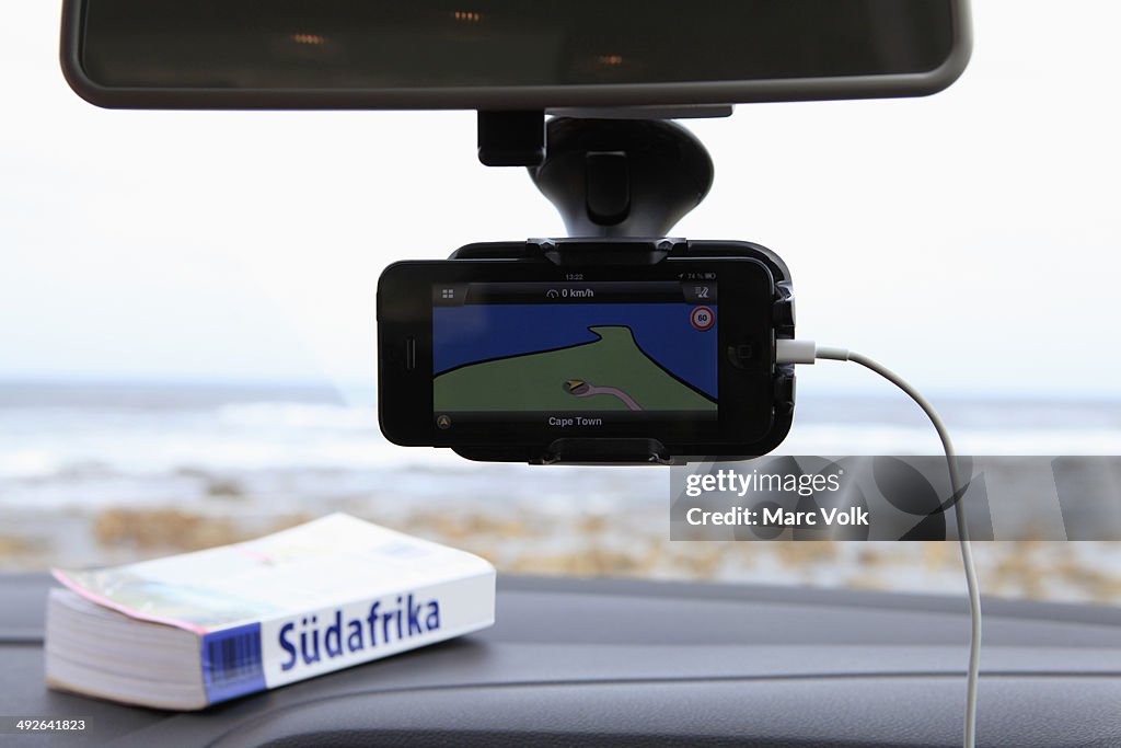 A GPS and South African guidebook on car dashboard