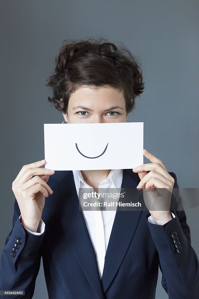 Portrait of mid adult woman holding paper with curve sign, close-up