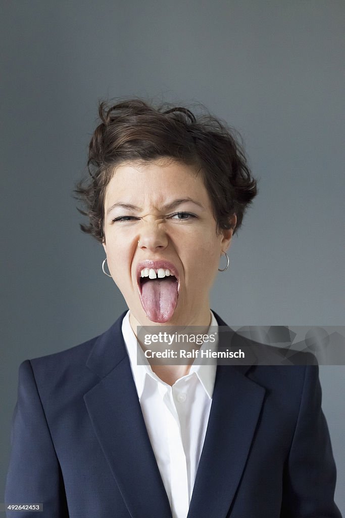 Mid adult woman sticking tongue out in disgust, close-up