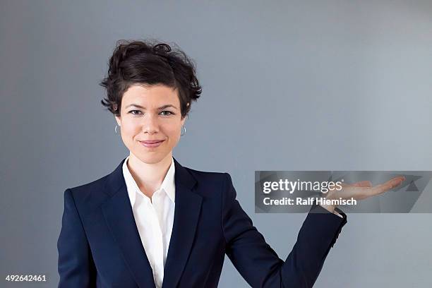 a smiling mid adult woman with her palm out in anticipation - suit hand stock-fotos und bilder