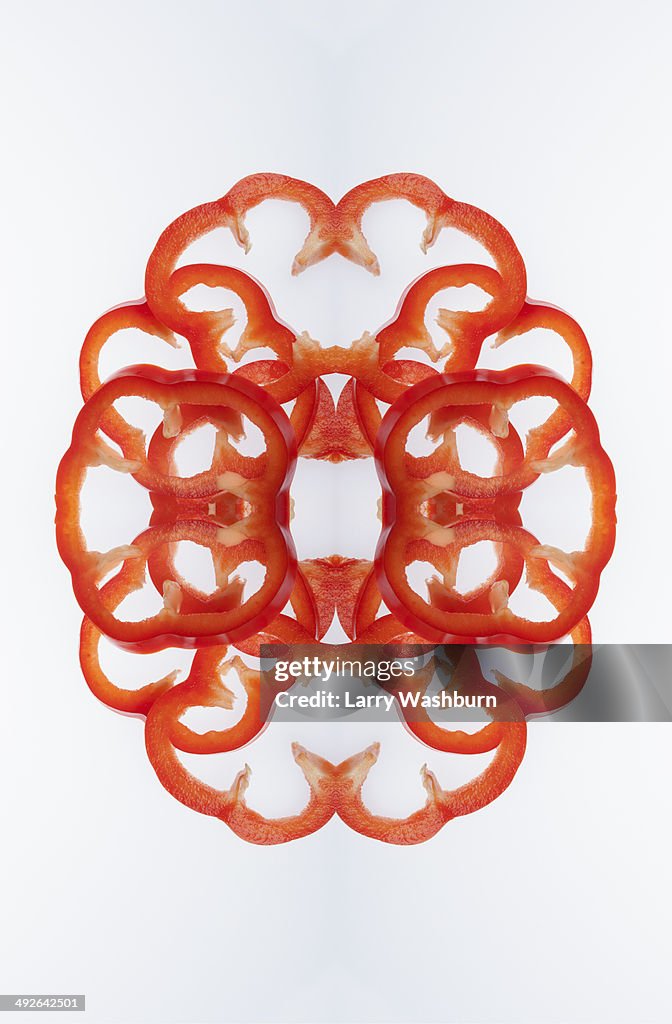 A digital composite of mirrored images of slices of red bell pepper