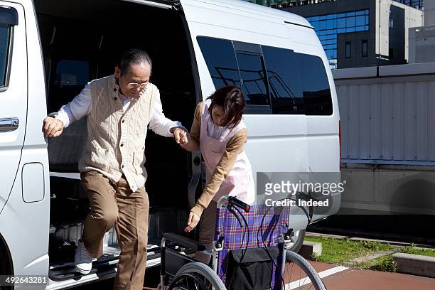 caregiver helping senior man to get out of van - rolstoelvriendelijk stockfoto's en -beelden