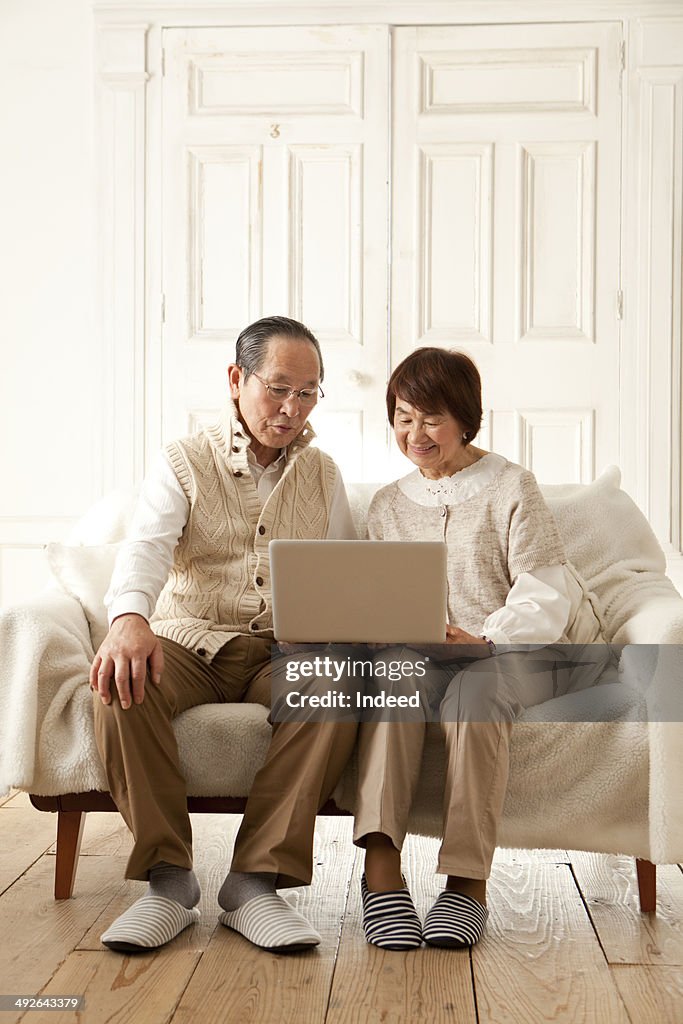 Senior couple looking at laptop screen on sofa
