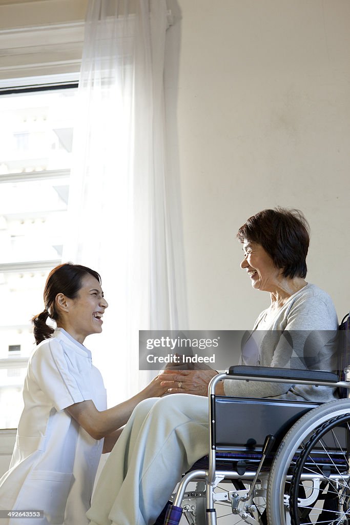 Female nurse and senior woman in wheelchair smiling face to face