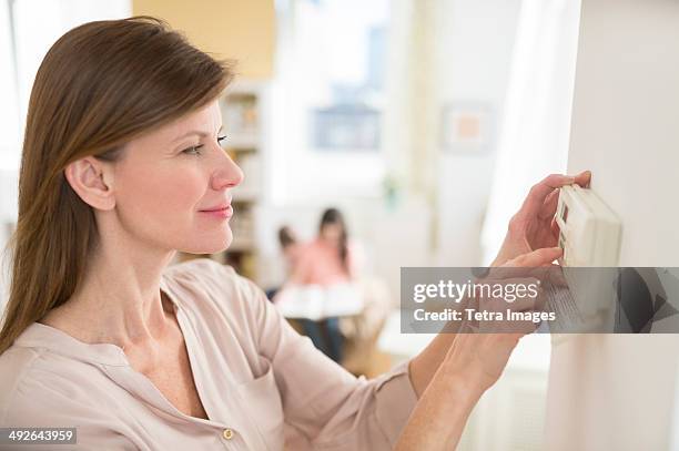 woman adjusting house alarm, jersey city, new jersey, usa - bijstellen stockfoto's en -beelden