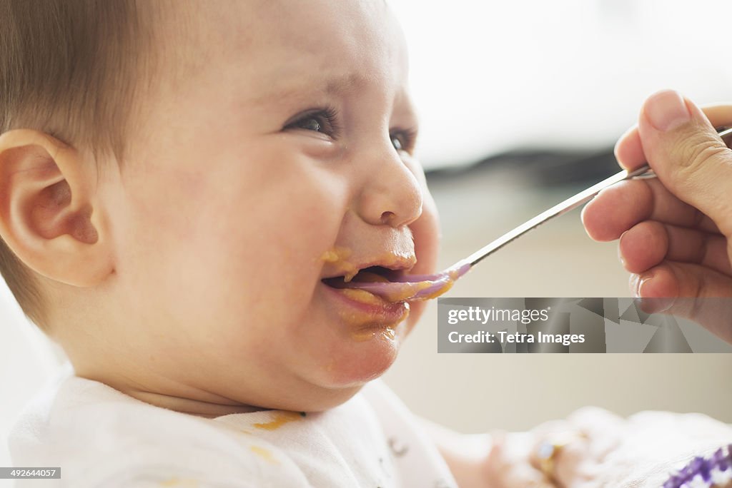 Close-up of baby girl (12-17 months) being spoon fed, Jersey City, New Jersey, USA