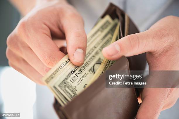 young man holding wallet and counting money, jersey city, new jersey, usa - wallet stockfoto's en -beelden