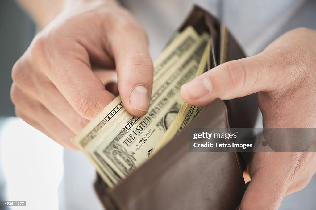 Young man holding wallet and counting money, Jersey City, New Jersey, USA