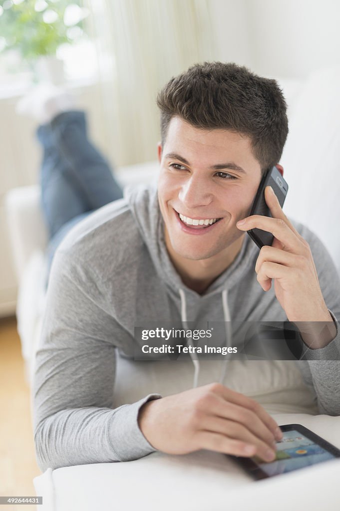 Young man using tablet and talking by phone, Jersey City, New Jersey, USA