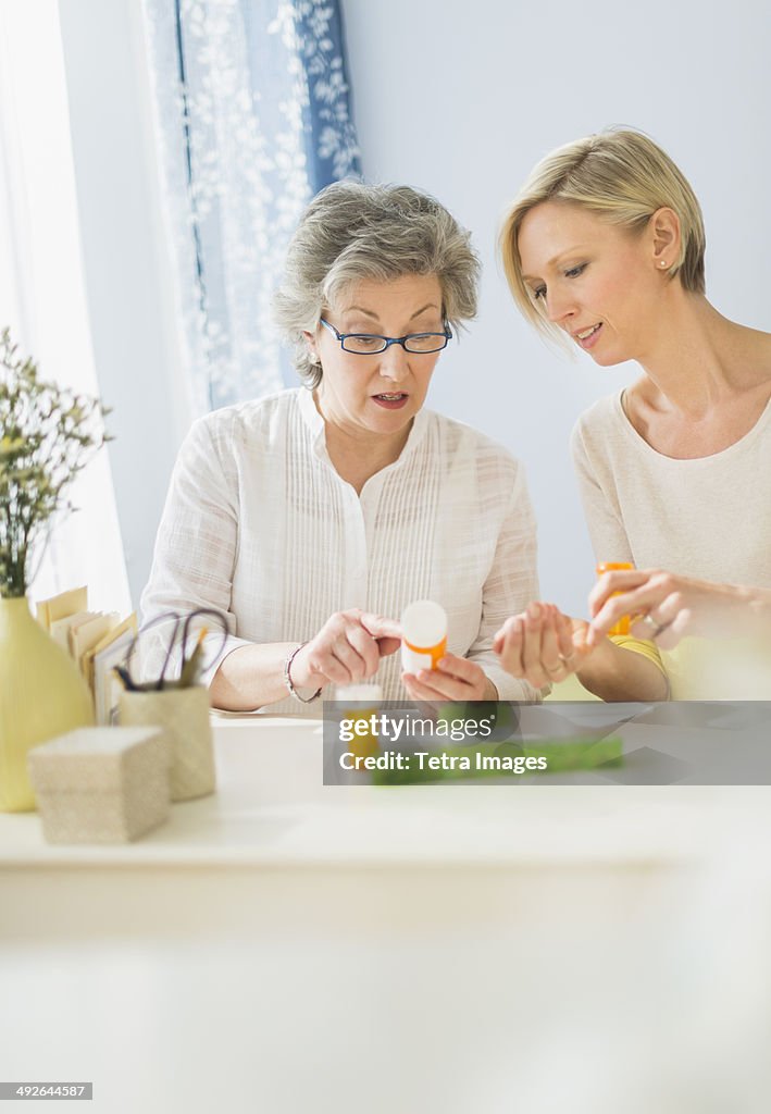 Nurse and mature woman reading labels on medicine bottle, Jersey City, New Jersey, USA