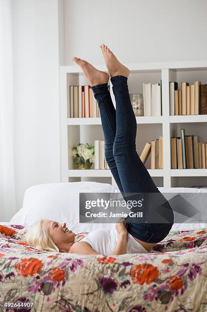 woman putting on skinny jeans on bed, jersey city, new jersey, usa - buttoning stock pictures, royalty-free photos & images