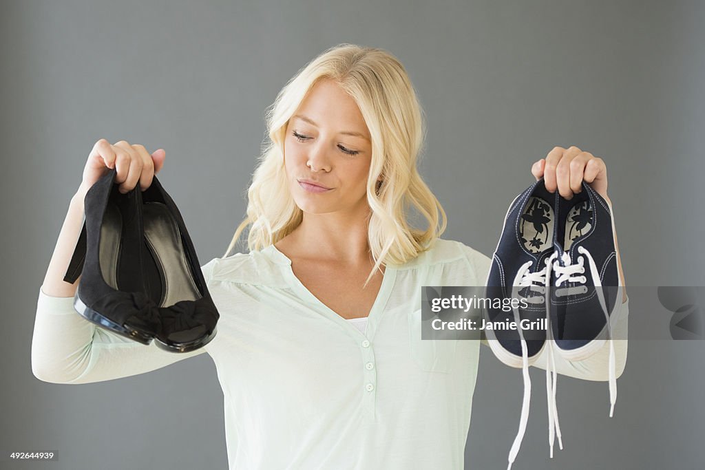 Portrait of young woman holding shoes, Jersey City, New Jersey, USA