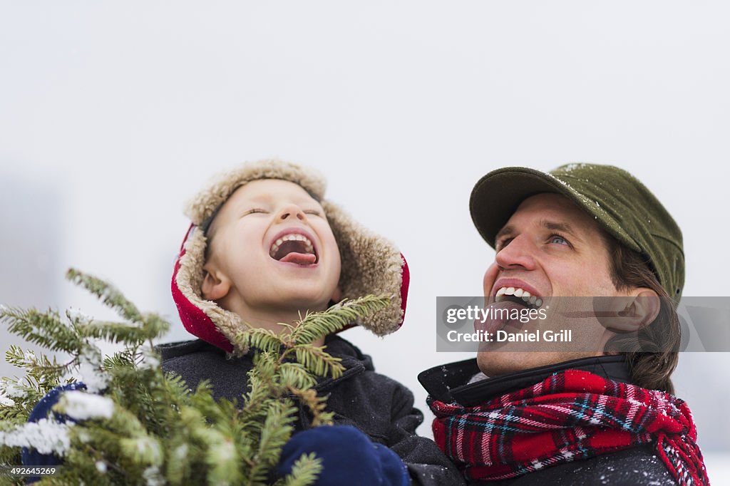 Father and son (6-7) catching snowflakes on tongue, Jersey City, New Jersey, USA