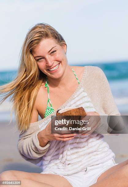 young woman on beach drinking coconut juice, jupiter, florida, usa - coconut water stock pictures, royalty-free photos & images