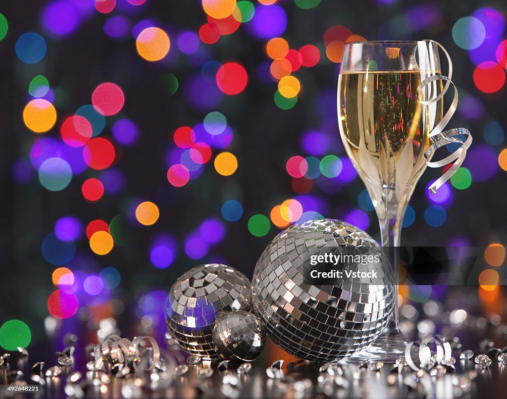 Champagne glass and disco balls on colorful background