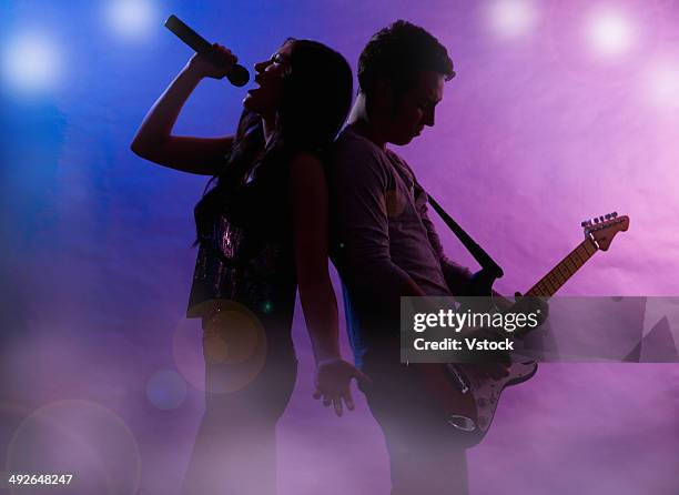 silhouettes of singer and guitar player on stage - duet stockfoto's en -beelden