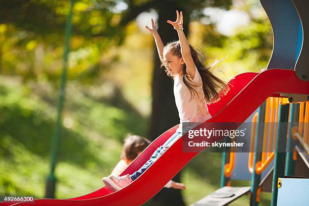 little girl sliding with her arms raised. - sliding stock pictures, royalty-free photos & images