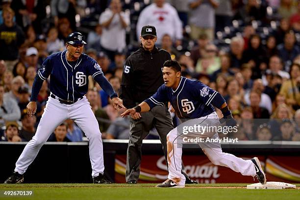 Everth Cabrera is congratulated by Glenn Hoffman of the San Diego Padres after sliding safely into third on a throwing error in the game against the...