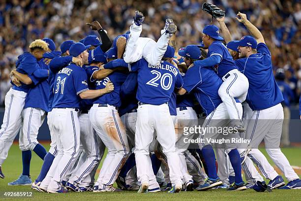 The Toronto Blue Jays celebrate the 6-3 win against the Texas Rangers as Ben Revere jumps on top of the pile in game five of the American League...