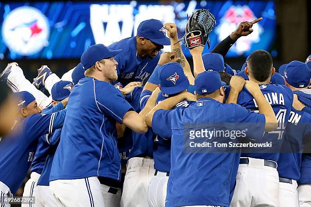 The Toronto Blue Jays celebrate the 6-3 win against the Texas Rangers as Ben Revere jumps on top of the pile in game five of the American League...