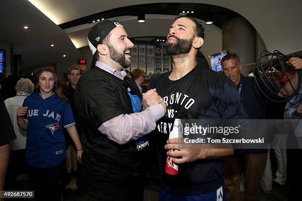 General manager Alex Anthopoulos and Jose Bautista of the Toronto Blue Jays celebrate the 6-3 win against the Texas Rangers as Ben Revere jumps on...