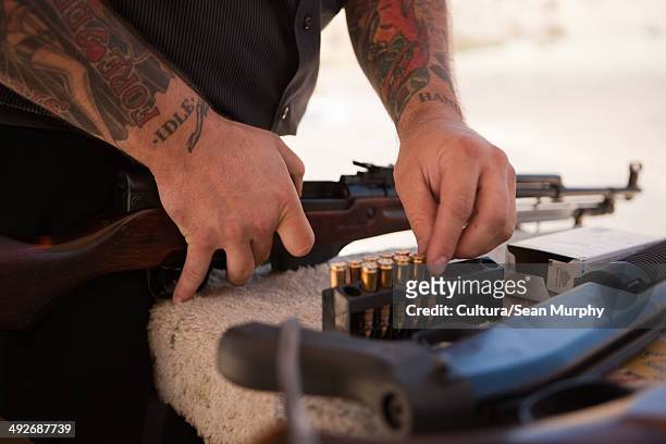 tattooed man loading rifle - cultura americana stock pictures, royalty-free photos & images