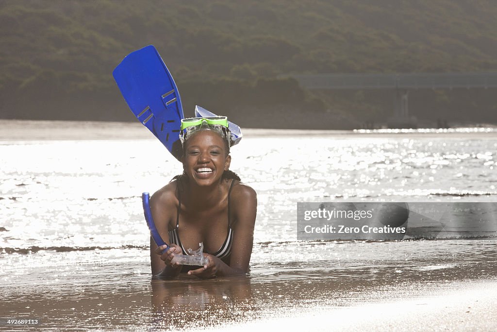 Young woman lying on beach, wearing snorkel