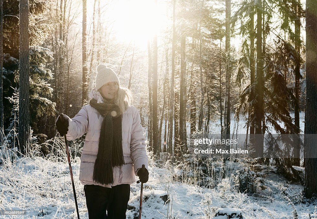 Mid adult woman nordic walking in snow covered forest