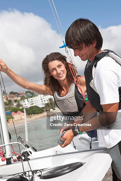 two young friends taking preparing sailboat in harbor - sailor shorts photos et images de collection