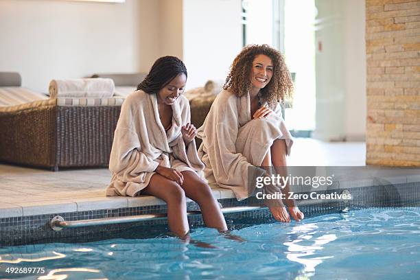 two young women relaxing on edge of spa swimming pool - spa stock pictures, royalty-free photos & images