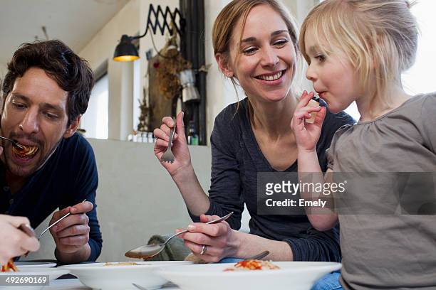 mid adult parents and two daughters eating a spaghetti meal - essen mund benutzen stock-fotos und bilder