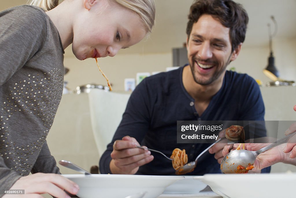 Mid adult man and family eating a spaghetti meal