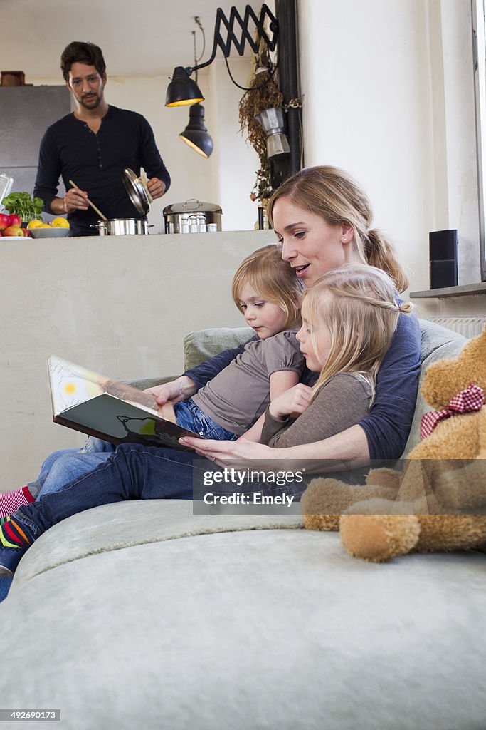 Mother and two daughters reading storybook