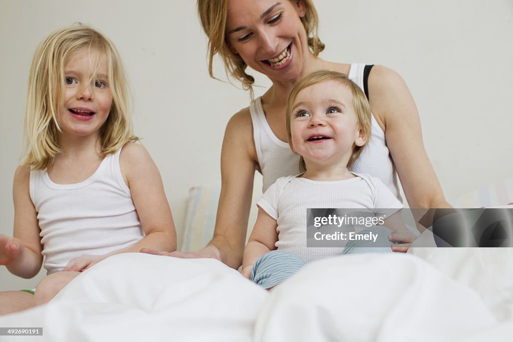 Portrait of mid adult woman in bed with two daughters