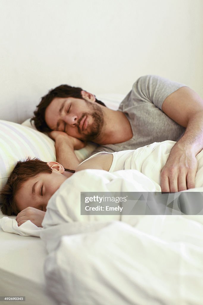 Father and young son sleeping in bed