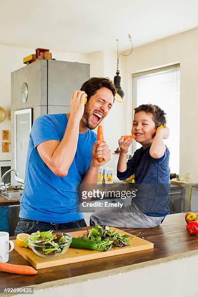 father and young son singing into carrot microphones - family singing stock pictures, royalty-free photos & images