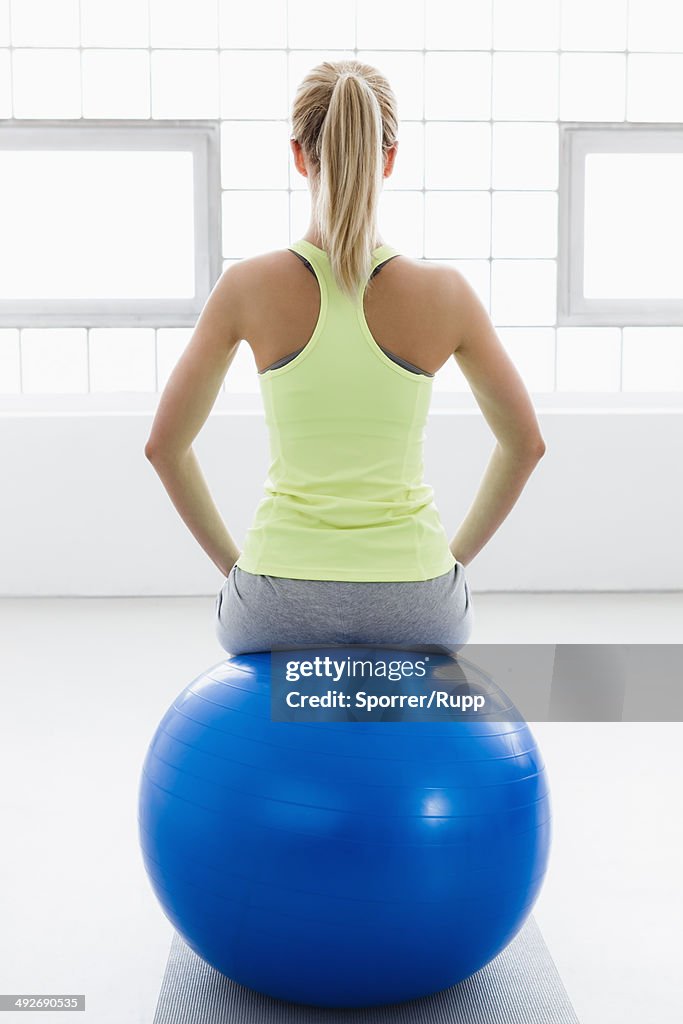 Young woman sitting on exercise ball, rear view