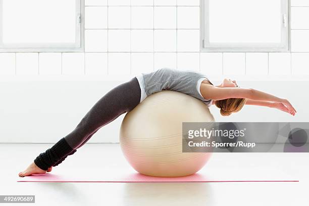 young woman stretching on exercise ball - fitness ball stock pictures, royalty-free photos & images