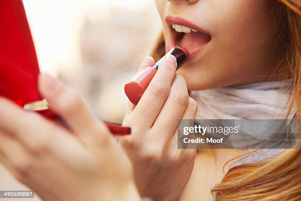 close up of young woman putting on lipstick - applying stockfoto's en -beelden