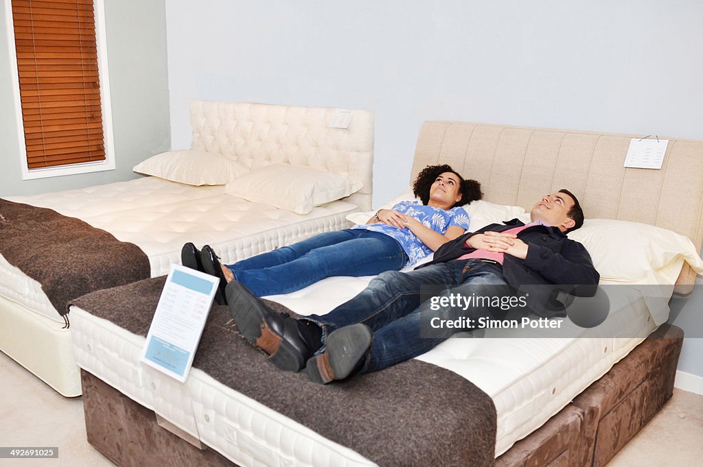 Couple lying on bed in furniture shop showroom