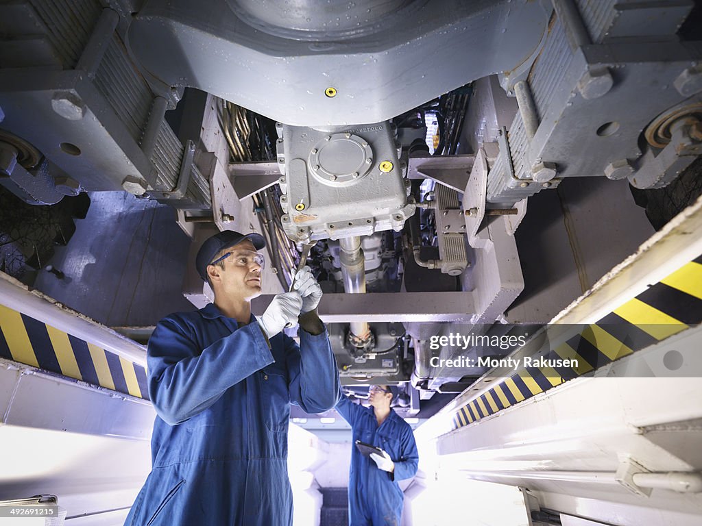 Engineers underneath truck in repair factory