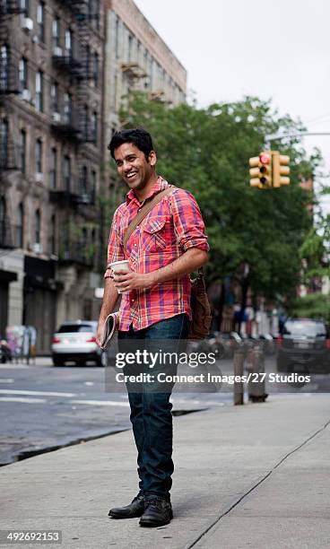 young man walking along city street, smiling - cultura orientale photos et images de collection