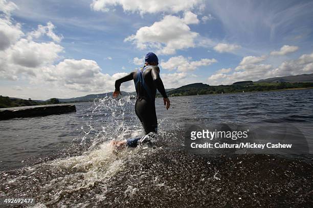 triathlete swimmer running into water - triathlon swim stock pictures, royalty-free photos & images