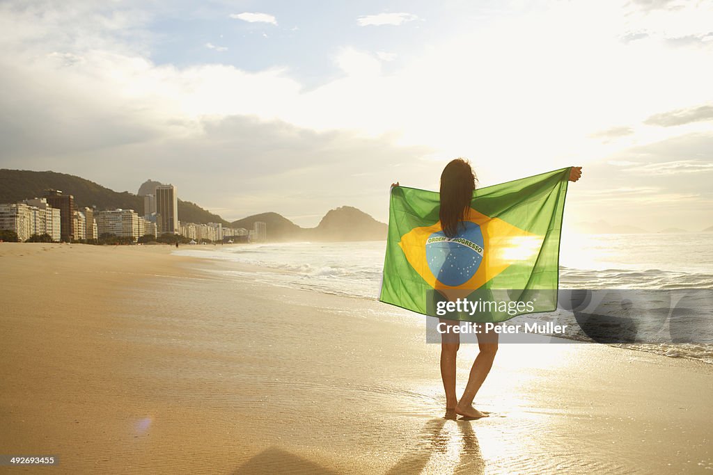 Woman holding Brazilian flag on Copacabana Beach, Rio, Brazil